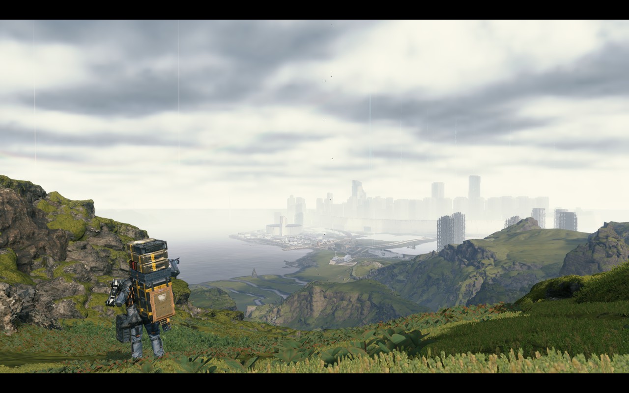 Death Stranding: protagonist in the foreground surrounded by hills with a city far in the background.