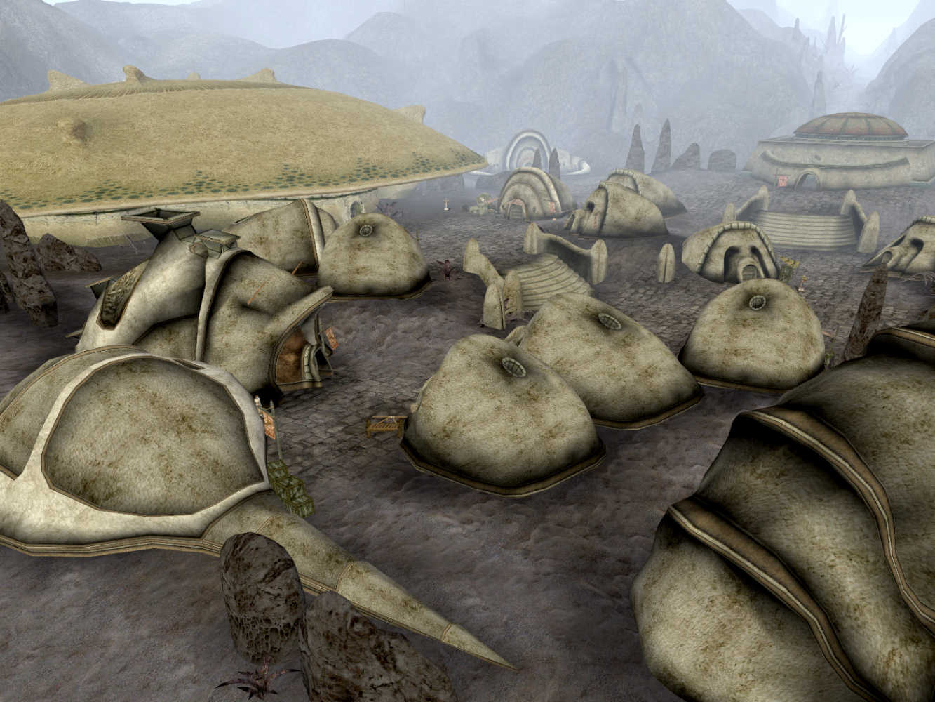 City of Ald'ruhn in Morrowind, featuring unique structures built from giant crab shells and various dome-shaped dwellings on a dusty landscape.