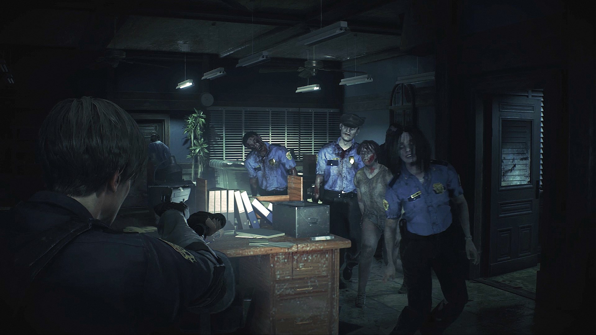 A screenshot from Resident Evil 2 (2019) shows main character attacked by zombies in a dimly lit police station interior.