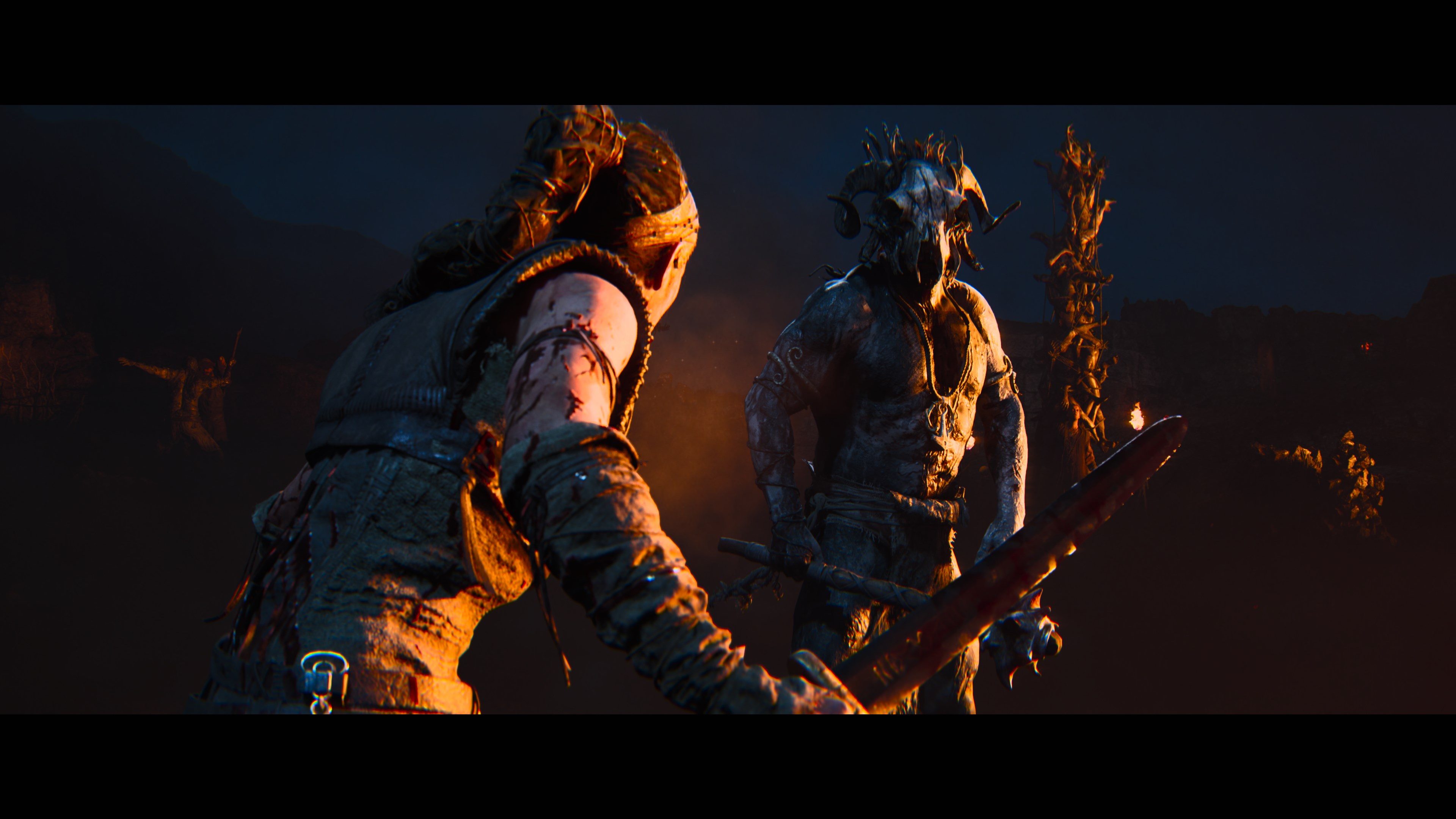 A screenshot from Senua’s Saga: Hellblade II shows two warrior-like figures in a dark, atmospheric setting, one holding a flaming torch.