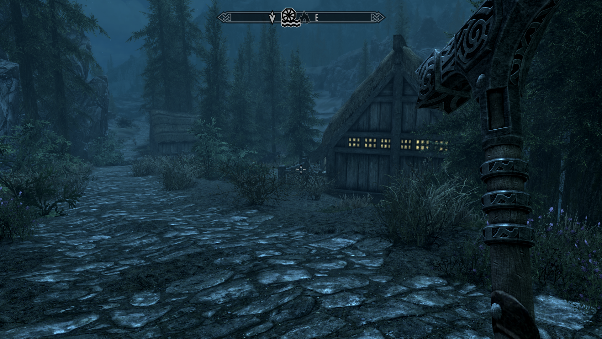 First person view of The Elder Scrolls V: Skyrim, a protagonist wielding a warhammer walking through the town.