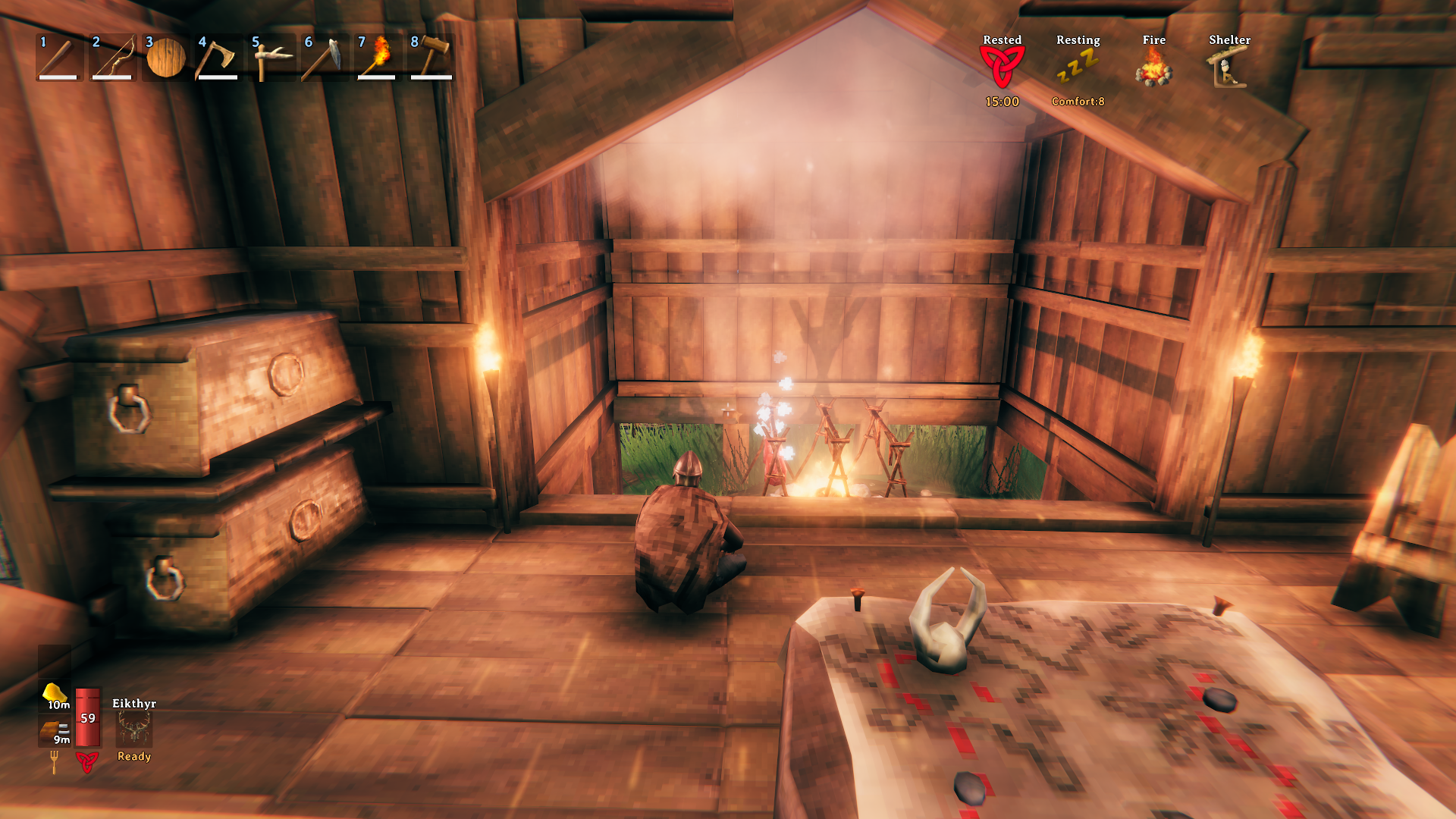 Protagonist of Valheim sitting in front of a hearth, cooking some meat. Screenshot by author.